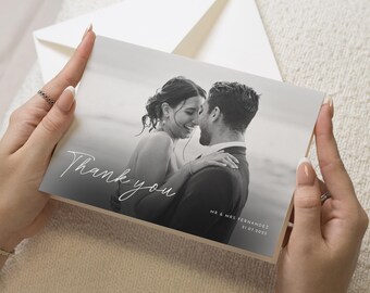 May include: A black and white wedding thank you card held by hands. The card features a photo of a couple embracing, with the words "Thank you" in script. The card also includes the names "MR & MRS FERNANDEZ" and the date "21.07.2023".