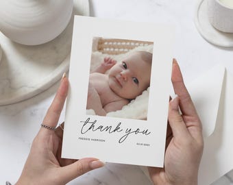 May include: A white thank you card with a photo of a baby in a white blanket. The card says "thank you" in cursive with the name "Freddie Harrison" and the date "03.01.2023" below.