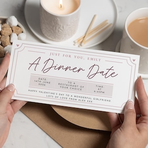Peut inclure: Une personne tient un bon cadeau "A Dinner Date". Le bon est blanc avec un texte violet foncé et une bordure décorative. Le texte comprend une date, une heure et un message. Une bougie allumée et une tasse de thé sont en arrière-plan.