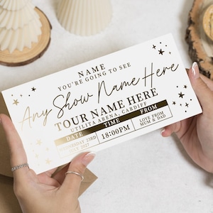 May include: A white and gold ticket with the text "Any Show Name Here" and "Tour Name Here". The ticket includes the date, time, and location. The text "Love from Mum & Dad" is also present.