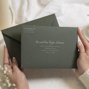 Peut inclure: Une enveloppe vert olive foncé avec du texte imprimé en blanc. Le recto affiche l'adresse de Mr and Mrs Taylor Johnson au 885 Richmond Road, Doncaster, South Yorkshire, DN83 2HE, avec une adresse de retour en haut à gauche indiquant Please Reply To 34 The Crescent, Broxill, BQ11 9QJ.