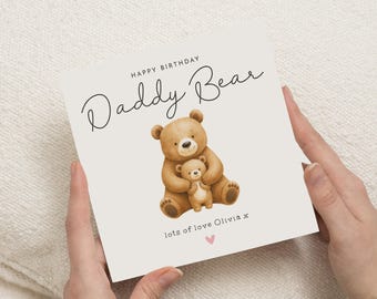 Może przedstawiać: Kwadratowa kartka z życzeniami z napisem "HAPPY BIRTHDAY Daddy Bear" czarnym pismem. Akwarelowa ilustracja dużego brązowego misia obejmującego mniejszego misia znajduje się pośrodku. Słowa "lots of love Olivia x" i różowe serce znajdują się na dole.