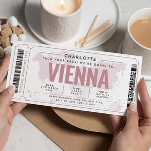 Puede incluir: Un pase de embarque personalizado para Viena, con el nombre "Charlotte" en la parte superior. El pase incluye la fecha, la hora y el aeropuerto de salida. Se incluye el mensaje "Happy Birthday! Have the best time. Lots of love Lucy & Josh".