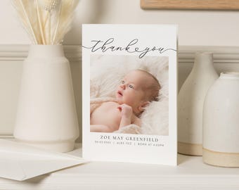 May include: Thank you card with a photo of a baby in a white blanket. The card says "Thank you" in a script font and includes the baby's name, birthdate, weight, and time of birth.  The card is white with black text.