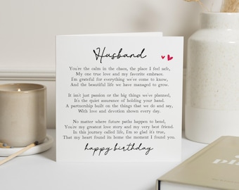 May include: A white greeting card with the word "Husband" in cursive and the words "happy birthday" at the bottom. The card has a poem about love and appreciation. Two small red hearts are above the poem.