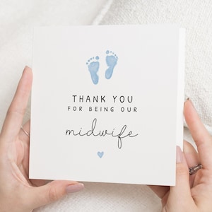 Könnte beinhalten: Eine quadratische weiße Karte mit blauen Babyfüßen und dem Text "THANK YOU FOR BEING OUR midwife" in schwarzer Schrift. Ein kleines blaues Herz befindet sich unter dem Wort "midwife".