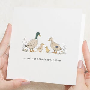 Könnte beinhalten: Eine quadratische weiße Grußkarte mit einer zentralen Illustration von zwei erwachsenen Enten und zwei kleinen Entenküken, die in einer Reihe stehen. Unter den Enten steht der Text ... and then there were four in einfacher, dunkelgrauer Schrift.