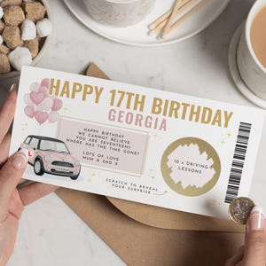 Peut inclure: Une carte à gratter d'anniversaire avec le texte "HAPPY 17TH BIRTHDAY GEORGIA" en or et rose. La carte présente une illustration de voiture rose, des ballons et une section pour "10 x DRIVING LESSONS".