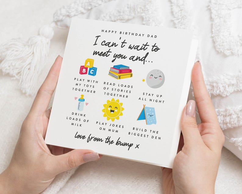 May include: A white card with a colourful illustration of a baby's toys and activities. The card reads "Happy Birthday Dad I can't wait to meet you and..." and lists activities like "Play with my toys together", "Read loads of stories together", "Stay up all night", "Drink loads of milk", "Play jokes on Mum", and "Build the biggest den". The card ends with "Love from the bump x".