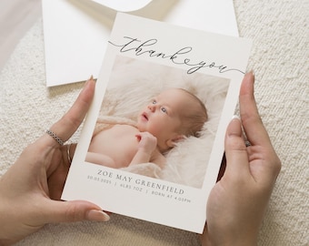 May include: Thank you card with a white background and black calligraphy. The card features a photo of a baby girl in a white blanket. The text on the card reads "Thank you" and "Zoe May Greenfield 02.03.2023 | 6lbs 7oz | Born at 4:03PM".