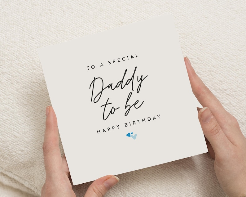 May include: A white card with black text that reads "To a special Daddy to be Happy Birthday" with two blue hearts.