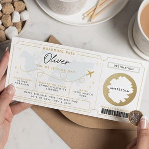 May include: A boarding pass with gold and white accents, featuring the name "Oliver" and the phrase "You're jetting off!" The destination is Amsterdam, with a scratch-to-reveal area. The date is March 22nd, 2026.