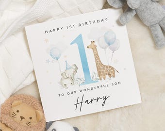 Puede incluir: Una tarjeta de cumpleaños azul y blanca con una ilustración de acuarela de una jirafa y un elefante. La tarjeta dice "Feliz 1er cumpleaños a nuestro maravilloso hijo Harry".