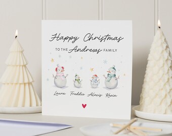 May include: A Christmas card with the message "Happy Christmas to the Andrews Family." The card features watercolor illustrations of snowmen wearing scarves and hats. The names Laura, Freddie, Alexis, and Kevin are printed below the snowmen.