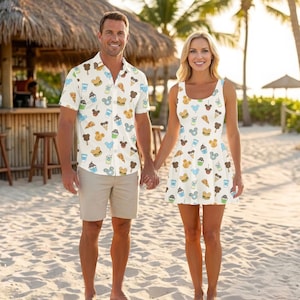 May include: A short-sleeved button-down shirt and a sleeveless dress, both featuring an all-over print of Mickey Mouse-shaped snacks, ice cream cones, burgers, and drink cups on a white background. The shirt is paired with beige shorts.