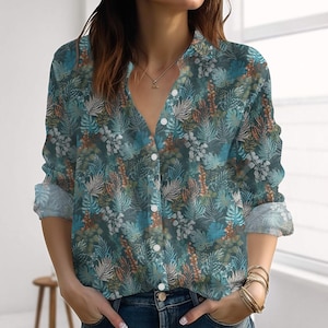 Può includere: Camicia button-down con stampa botanica nei toni del verde acqua, blu e arancione. La camicia a maniche lunghe ha uno scollo a V e bottoni bianchi. I polsini sono arrotolati, rivelando un tessuto più chiaro. La camicia è realizzata in materiale morbido e fluido.