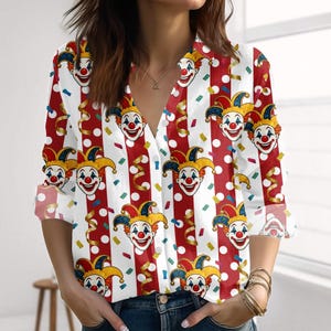 Könnte beinhalten: Ein Hemd mit Knöpfen und einem sich wiederholenden Muster aus Clown-Gesichtern, rot-weißen Streifen und weißen Punkten. Das langärmlige Hemd hat einen V-Ausschnitt. Konfetti und goldene Luftschlangen sind über das Design verstreut.