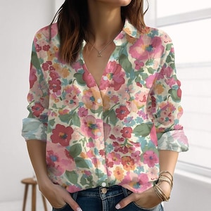 Könnte beinhalten: Ein floral bedrucktes Hemd mit einem Muster aus rosa, roten und orangen Blumen auf cremefarbenem Hintergrund. Das langärmlige Hemd hat einen klassischen Kragen und ist vorne geknöpft.