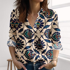 Op de afbeelding: Beige overhemd met knopen en een bloemenpatroon in teal, rood en marineblauw. Het shirt met lange mouwen heeft een klassieke kraag en manchetten met knopen. Het bloemenpatroon wordt herhaald over de stof.