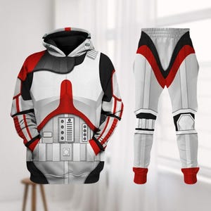 Peut inclure: Un ensemble de sweat à capuche et de pantalon blancs, rouges et noirs. Le sweat à capuche présente un design détaillé avec une capuche, des poches et une fermeture éclair sur le devant. Le pantalon a un design similaire avec des accents rouges. L'ensemble est conçu pour ressembler à un costume.