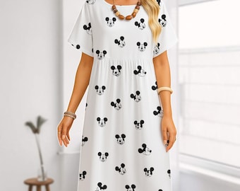 May include: White, short-sleeved dress featuring a pattern of black Mickey Mouse faces. The dress has a round neckline and a gathered waist. The model is wearing jewelry, including a necklace and bracelets. The dress is knee-length.