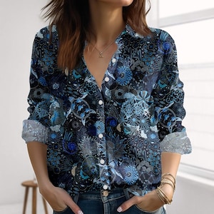 Könnte beinhalten: Ein dunkelblaues Hemd mit floralem Muster und Knöpfen. Das langärmlige Hemd hat einen V-Ausschnitt und weiße Knöpfe. Die Manschetten sind hochgekrempelt und zeigen ein helleres blau-weißes Muster. Das Hemd ist aus weichem, bequemem Material.