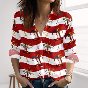 Könnte beinhalten: Ein Button-Down-Hemd mit rot-weißem Streifenmuster. Das Hemd hat ein sich wiederholendes Design von Narrenstiefeln und -hüten mit bunten Luftschlangen. Das langärmlige Hemd hat einen Kragen und ist aus leichtem Stoff gefertigt.