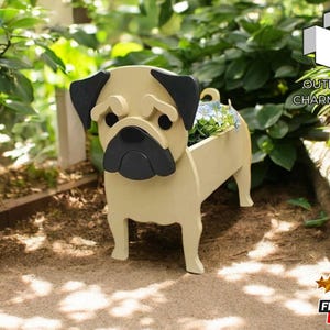 May include: A beige wooden planter shaped like a pug dog with black ears and a black nose. The planter is filled with green plants and flowers. The planter is sitting on a brown surface.
