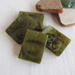 May include: Four green rectangular tiles with a marbled pattern. The tiles are made of glass or resin and have a translucent appearance.