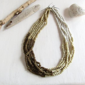 May include: A multi-strand necklace made of brown, beige and white beads. The beads are small and round, and the necklace is graduated in colour, with the brown beads at the top and the white beads at the bottom.