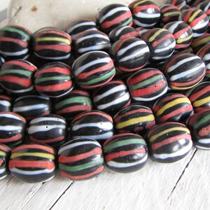 May include: A collection of black glass beads with colorful stripes. The beads are oval shaped and have a glossy finish.