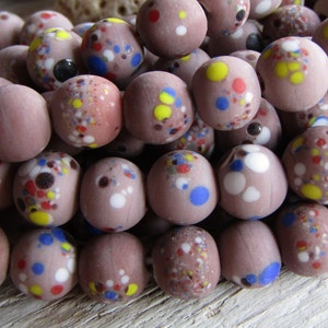 Può includere: Una collana di perline di vetro marrone con macchie colorate. Le perline sono rotonde e hanno una finitura opaca.