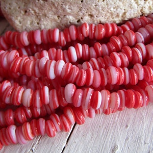 Può includere: Una collana di perline di vetro a strisce rosse e bianche. Le perline sono rotonde e hanno una finitura liscia e lucida.