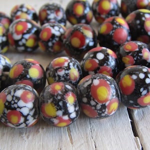 Può includere: Una collana di perline di vetro nero con pois bianchi e rossi. Le perline sono rotonde e hanno una finitura lucida.