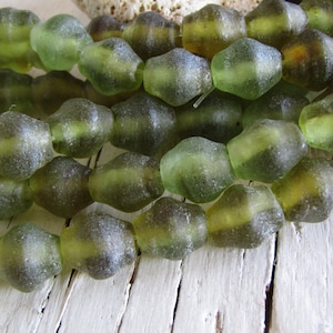Op de afbeelding: Een streng groene glazen kralen met een onregelmatige, gefacetteerde vorm. De kralen hebben een mat, doorschijnend uiterlijk.