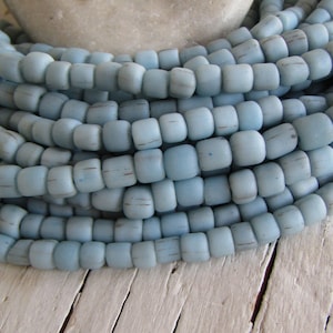 May include: A strand of light blue glass beads, each bead is slightly irregular in shape and has a matte finish.