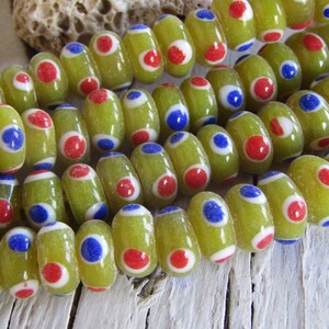 Può includere: Una collana di perline di vetro verde con pois rossi e blu. Le perline sono di forma ovale e hanno una finitura lucida.