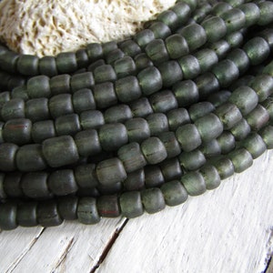 May include: A strand of dark green glass beads. The beads are round and have a matte finish.