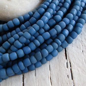 Op de afbeelding: Een streng blauwe glazen kralen, elke kraal is licht afgerond en heeft een matte afwerking.