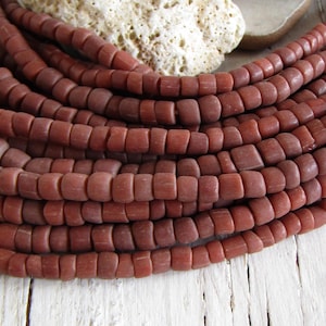 May include: A strand of reddish-brown square beads. The beads are made of natural stone and have a matte finish.