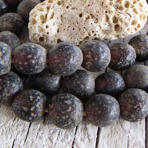 Op de afbeelding: Een streng donkergrijze en paarse kralen met een gespikkelde textuur. De kralen zijn rond en hebben een matte afwerking.