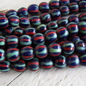 Può includere: Una collana di perline di vetro blu, rosso e verde. Le perline sono rotonde e hanno un motivo a strisce.