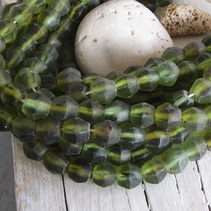 Può includere: Una collana di perline di vetro verde con forma esagonale sfaccettata. Le perline hanno un aspetto leggermente opaco e sono infilate su un filo trasparente.