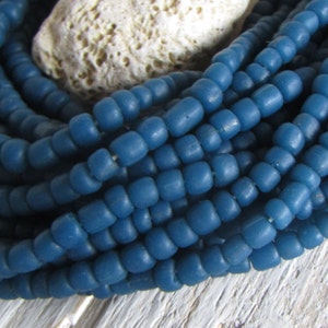 Op de afbeelding: Een streng donkerblauwe glazen kralen. De kralen zijn klein en rond en zijn in een close-up weergegeven.