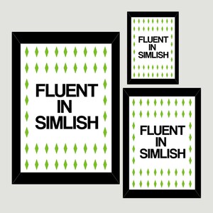 May include: Three black framed prints with a white background and green diamond patterns. The text "Fluent in Simlish" is printed in black on each print.