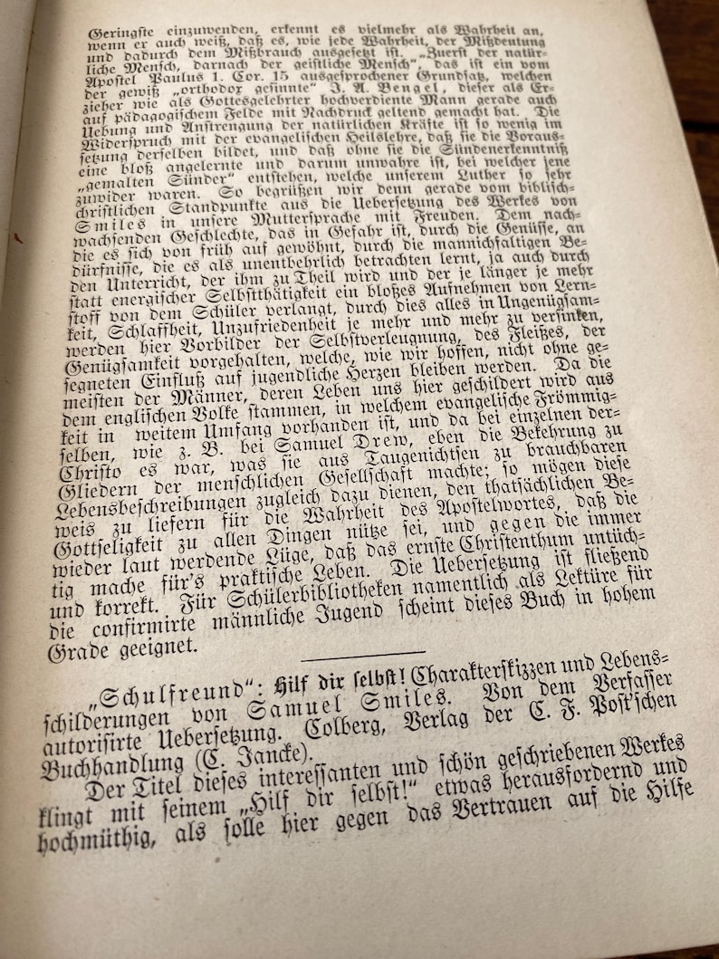 May include: A page from an antique book featuring dense black German text printed on aged, off-white paper. The text discusses religious and educational themes, including a reference to Samuel Smiles and the title Hilf dir selbst.