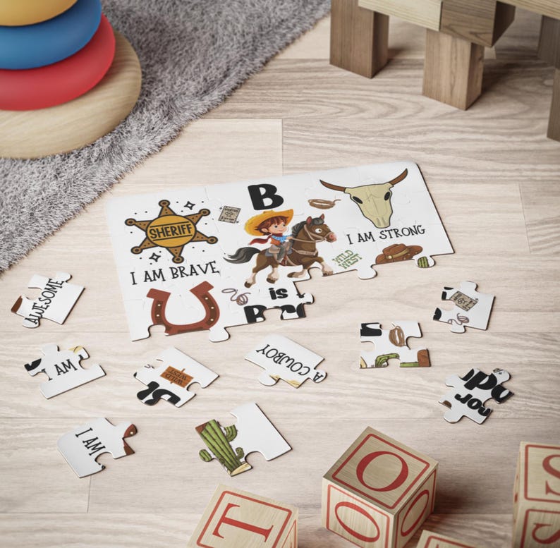 May include: A children's puzzle with a cowboy theme. The puzzle features a cowboy riding a horse, a sheriff's badge, and the text "I AM BRAVE". Additional puzzle pieces and wooden blocks with letters are scattered around.