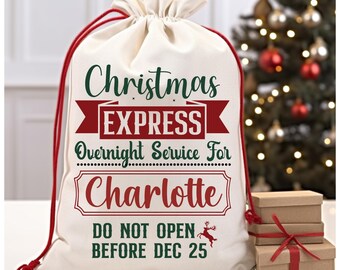 May include: White canvas Christmas gift bag with red and green text that reads "Christmas Express Overnight Service For Charlotte Do Not Open Before Dec 25".