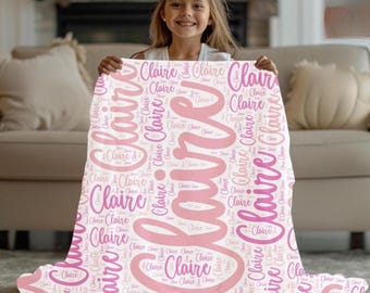 May include: A white blanket with the name "Claire" in a large, cursive font, surrounded by smaller instances of the name in a pink hue. The blanket is soft and appears to be made of a comfortable material.