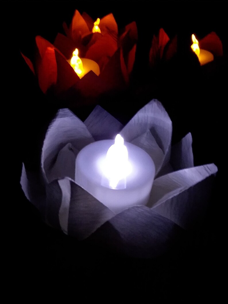 May include: Three paper lotus flower candle holders with LED tea lights. One holder is white with a white light, and two are red with orange lights.